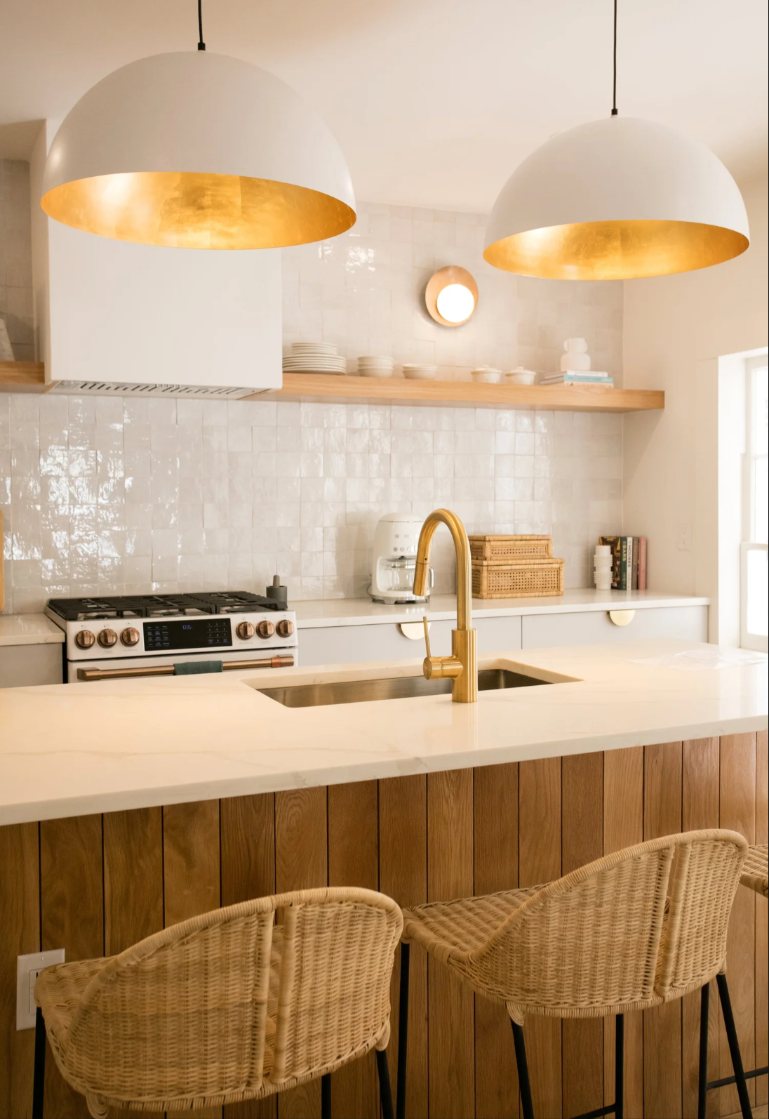 Bright kitchen with white zellige tile, brass faucet and woven counter stools