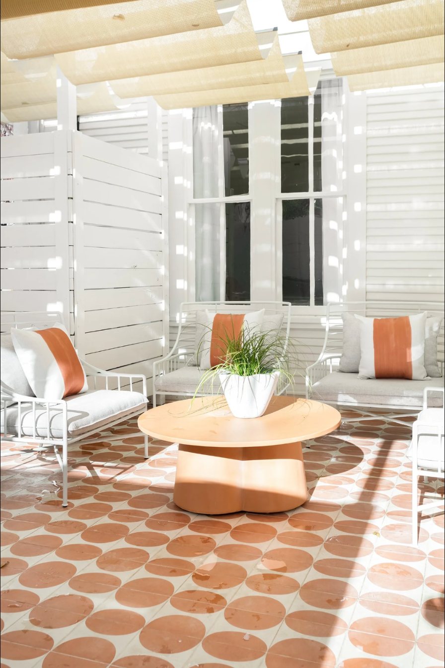 Sunny patio with terracotta circle tile, white lounge chairs and a sculptural coffee table