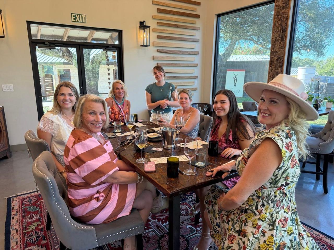 Friends smiling around a seated wine tasting in a Hill Country tasting room