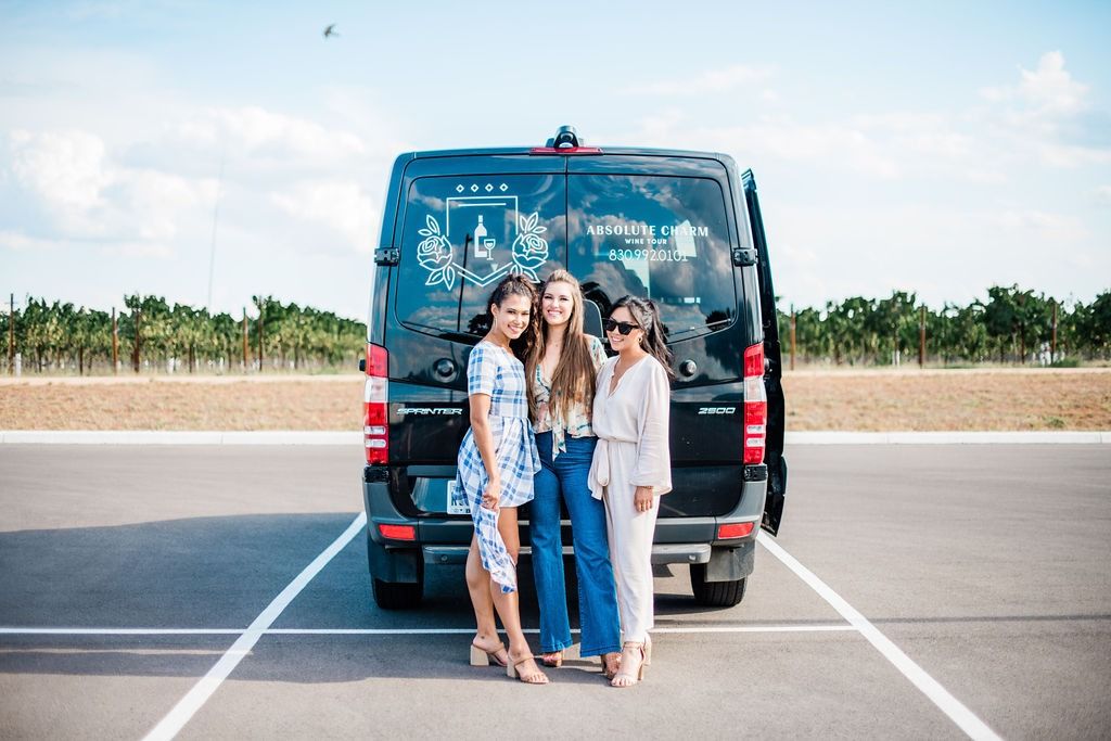 Three friends standing in front of the Absolute Charm Mercedes Sprinter van at a vineyard