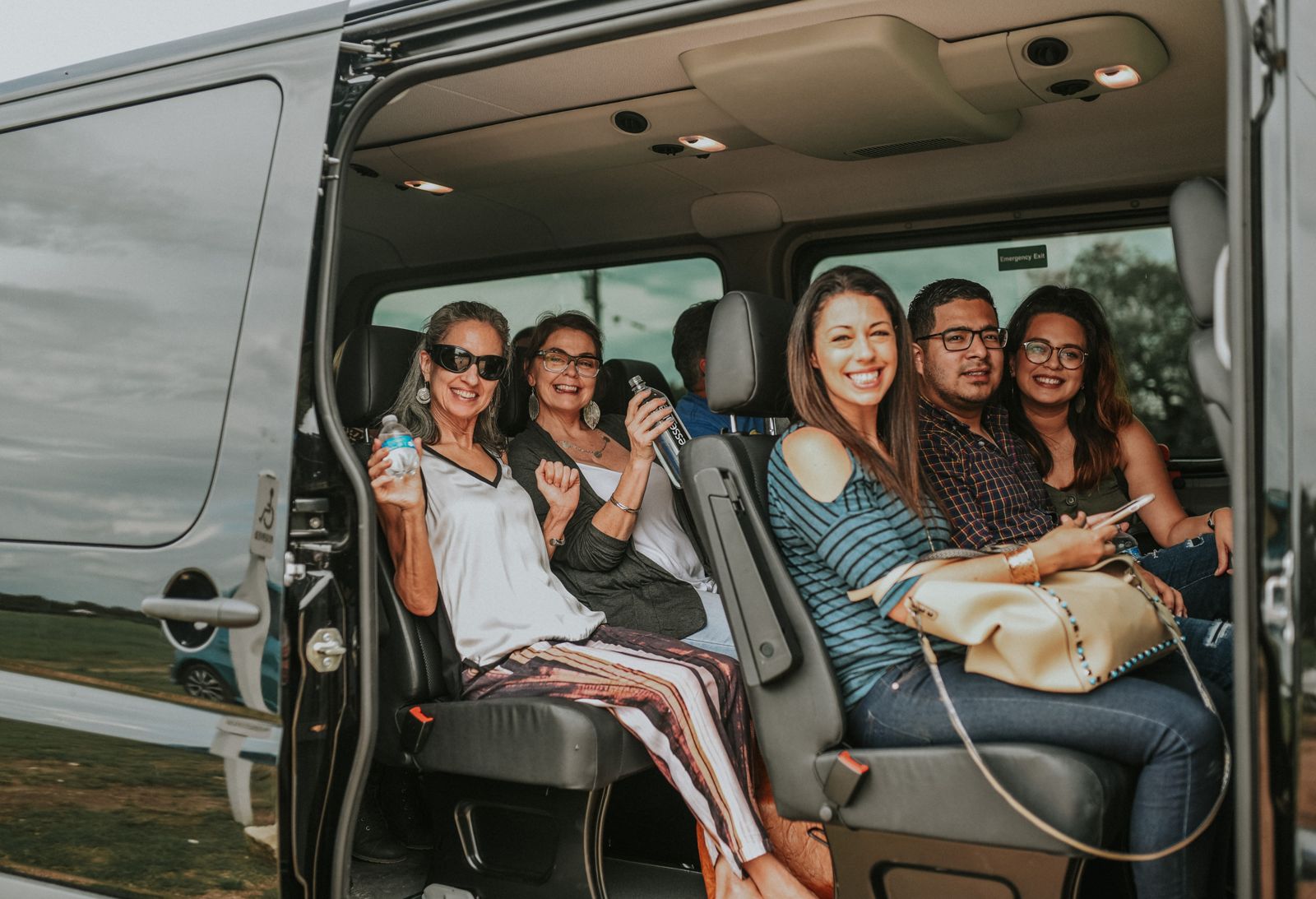 Smiling guests in the leather seats of the Absolute Charm Mercedes Sprinter